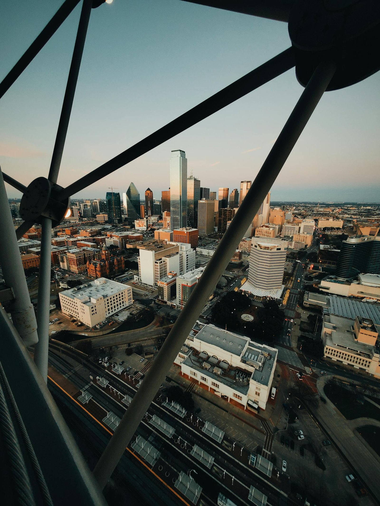 Aerial view of a bustling city skyline at sunset with modern skyscrapers and urban streets.
