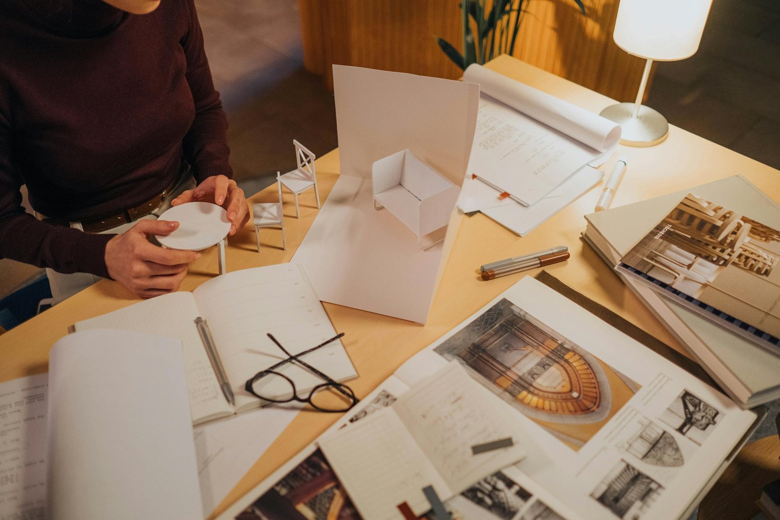 Architect reviewing a miniature model design on a desk full of sketches and plans.