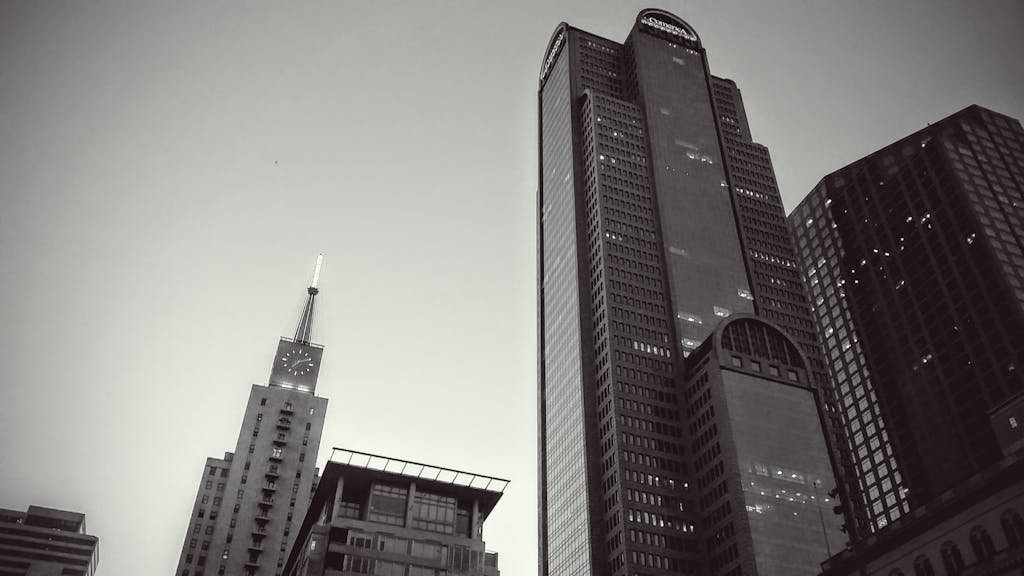 Black and white photo of tall modern skyscrapers in downtown cityscape.